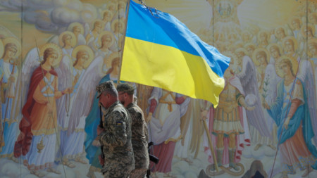 Украински военни с националния флаг на страната пред фреска на катедрала в Киев, 8 септември 2022 г.