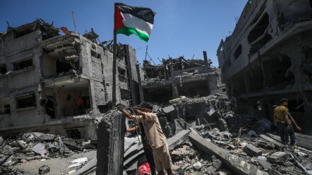 Палестинците издигат палестинско знаме до разрушената си къща след израелски въздушен удар срещу бежанския лагер Ал-Бурейдж, южната част на Ивицата Газа, 18 юни 2024 г.