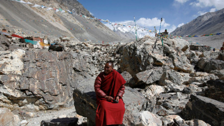 Монах си почива край манастир в Тибет.