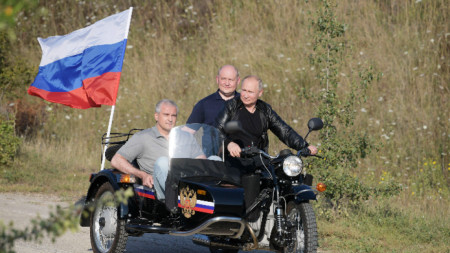 Владимир Путин (вдясно) управлява мотоциклета Ural с ръководителя на Крим Сергей Аксенов (вляво) и  ръководителя на Севастопол Михаил Развожаев (вдясно)
