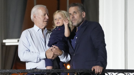 Джо Байдън, който държи внука си Бо, и синът му Хънтър Байдън на балкон в Белия дом, 4 юли 2022 г.