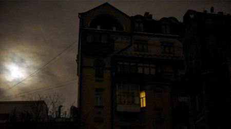 Прозорец свети в жилищен блок по време на спиране на електроподаването в Киев,  декември 2022
