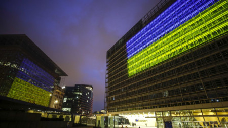 Сградата на Европейския съвет (вляво) и Европейската комисия са осветени в цветовете на украинското знаме, 23 февруари 2023 г.