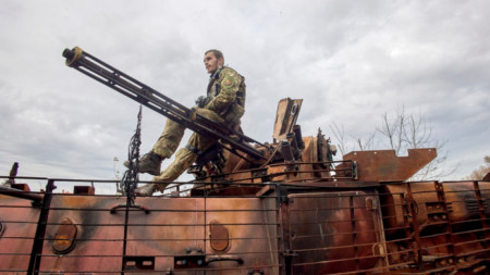Военнослужещ от Национална гвардия на Украйна седи върху унищожен бронетранспортьор в района на Харков, 25 октомври 2022 г.