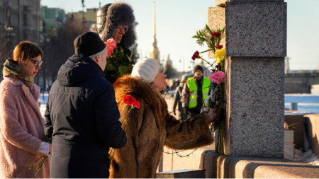 Menschen legen vor dem Denkmal für die Opfer politischer Repression in St. Petersburg Blumen zum Gedenken an Alexej Nawalni nieder, 18.02.2024