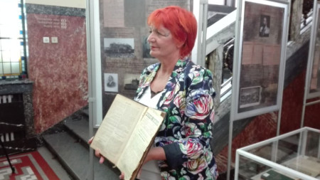Директорът на Столичната библиотека Юлия Цинзова показва стар брой на Държавен вестник.