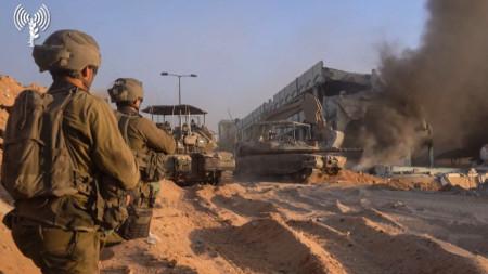 Израелски бойци в Газа наблюдават как булдозер разрушава горяща сграда.