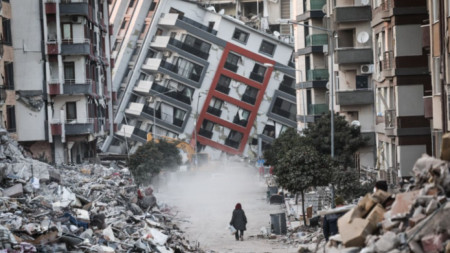 Жена върви между развалините на срутени от земетресението сгради в Хатай, Турция, 17 февруари 2023 г.