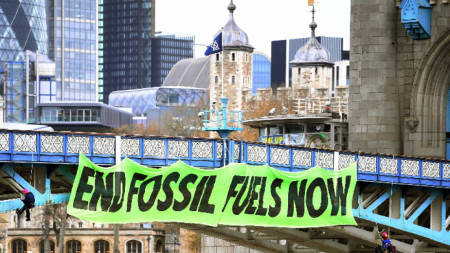 Членове на групата за натиск Extinction Rebellion висят на въжета и са окачили транспарант на Тауър Бридж в Лондон с надпис „Спрете изкопаемите горива сега“, 8 април 2022 г. 