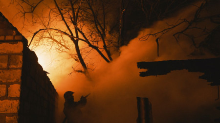 Огнеборец се опитва да потуши пожара в къща след руски обстрел на село Иванивка край Бахмут, Донецка област на Украйна, 2 януари 2023 г.