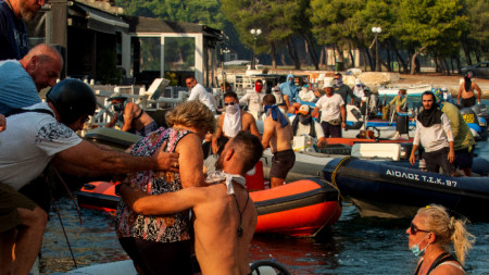 Хората се евакуират с лодки  от Неа Анхиалос, близо до Волос, Гърция, 27 юли 2023 г.