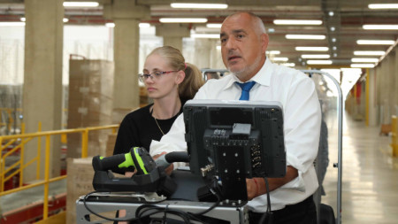 Премиерът кара мотокар при обиколката си в нов логистичен център край София.