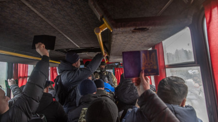 Пътуващи показват паспортите си на член на силите за териториална отбрана на контролно-пропускателен пункт в източната част на Киевска област, Украйна, 6 март 2022 г.