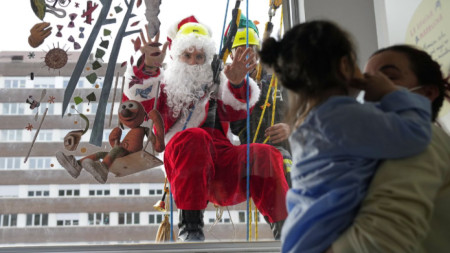 Дяко Коледа се опитва да зарадва деца в болница в Барселона, висейки на прозореца им