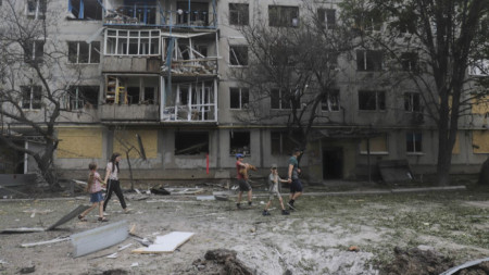 Местни жители преминават край жилищен блок с щети от обстрел в Бахмут, Донецка област, 13 юни 2022 г.