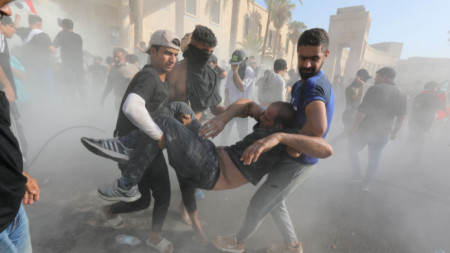 Привърженици на Муктада Садр помагат на пострадал при сблъсъци със силите за борба с безредиците край сградата на правителството в Багдад, 29 август 2022 г.