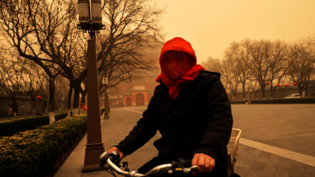 Жена е покрила лицето си с шал, за да се опази от пясъка в Пекин