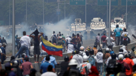 Бронирани машини се насочват към бунтуващи се демонстранти пред ВВС базата „Карлота“ в Каракас.  