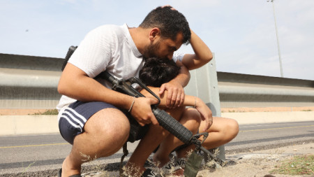 Въоръжен израелец със сина си в Тел Авив по време на ракетна атака от Газа, 27 октомври 2023 г.