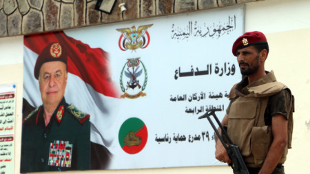 Войник на южните сепаратисти стои пред постер с лика на президентът Хади в Аден