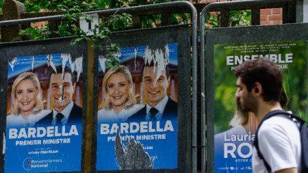 Мъж преминава покрай предизборни плакати с лика на лидерите на крайната десница Марин льо Пен и Жордан Бардела край Париж, 29 юни 2024 г.