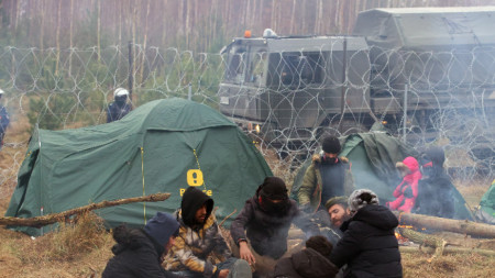 Мигранти на беларуско-полската граница в района на Гродно, Беларус, полски военнослужещи пазят зад оградата с бодлива тел, 10 ноември 2021 г.