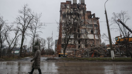 Жена преминава край полуразрушена сграда в Мариупол, 12 декември 2022 г.
