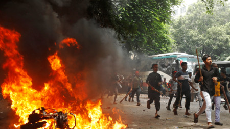 Участници в протестите в Дака тичат край запален мотоциклет до болницата на Медицинския университет - 4 август 2024 г.