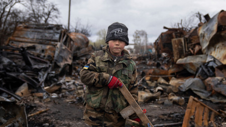 Седемгодишният Егор е застанал до унищожени руски бронирани машини край украинския град Чернигов на 17 април 2022 г. Снимка: АП