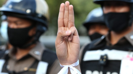 Вдигната ръка с три пръста и бяла панделка са символите на протеста в Тайланд.