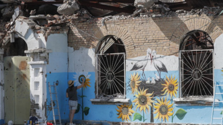 Уличната художничка Олена Янко рисува слънчогледи по оцеляла стена на център за социални и културни дейности в Ирпин край Киев, 22 август 2022 г.
