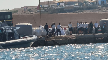 Служители на италианската брегова охрана носят чувал за трупове на кея на пристанището Лампедуза, след като лодка, превозваща близо 100 мигранти, се преобърна край италианския остров -  13 август 2025 г.