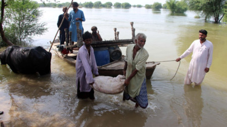 Хора пренасят мебели в наводнен район на Пакистан, 29 август 2022 г.