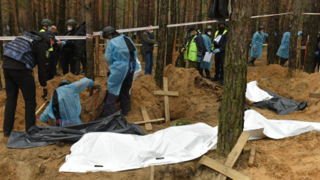 Работници ексхумират тела от гробове в Изюм, в района на Харков, 16 септември 2022 г.