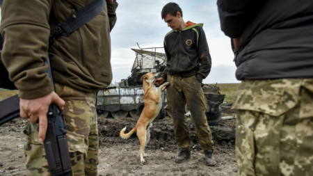 Украински военен си играе с куче край пленен руски танк в района на Харков, 30 септември 2022 г.
