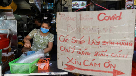Виетнамка продава храна в Ханой, надписът призовава към спазване на противоепидемичните мерки, 31 май 2021 г. 