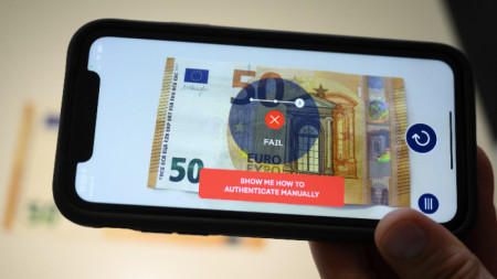 Банков служител проверява автентичността на евробанкнота с помощта на  приложение за смартфон на пресконференция в Koenig & Bauer Banknote Solutions в Лозана, Швейцария, архив, юни 2022 г.