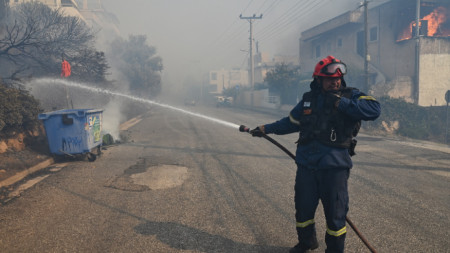 Пожарникар потушава пламъци от пожара край Атина, 17 юли 2023 г.