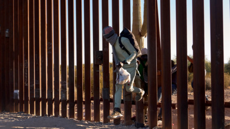 Мигрант преминава граничната ограда между Мексико и Аризона.