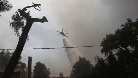 Снимката е илюстративна - противопожарен хеликоптер потушава горски пожар в района на Стамата, Гърция, 27 юли 2021 г. 