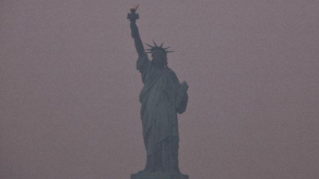 Статуята на свободата в Ню Йорк е обгърната от червеникав дим заради пожарите в Канада, 7 юни 2023 г.