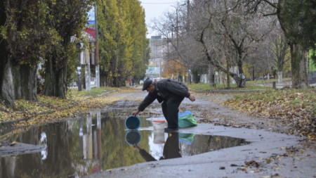 Мъж събира вода от локва в Херсон, където украинските сили влязоха след руското изтегляне, 18 ноември 2022 г.