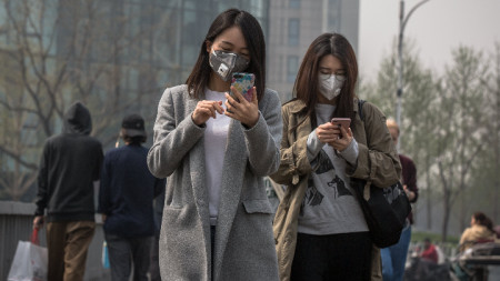 Жителки на Пекин носят защитни маски заради замърсяване на въздуха в китайската столица през април 2018 г.