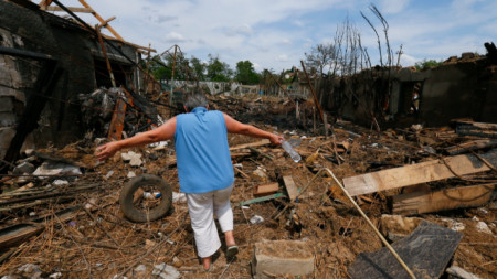 Жена оглежда разрушения си дом в околностите на Одеса, юни 2022 г.