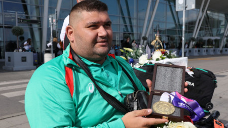Ружди показва златния медал на летището.