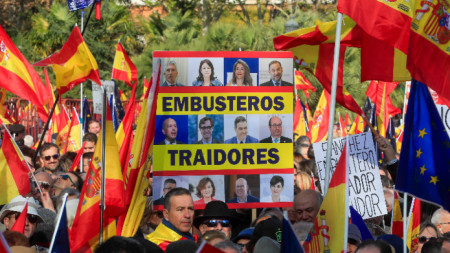 Демонстрант държи транспарант, изобразяващ испанския премиер Педро Санчес и някои от неговите министри, който гласи 