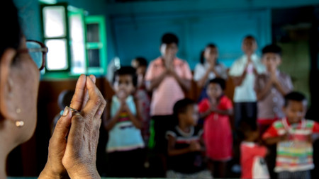 Учител, засегнат от проказа (вляво), се моли с деца на пациенти в Центъра за проказа 