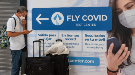 Мъж стои до реклама на център за Covid тестове на летище Барахас, Мадрид, 20 юни 2022 г.