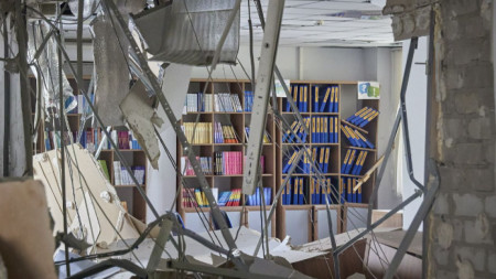 Лавици с книги се виждат през разрушения на сграда на колеж след руски обстрел на градчето Дергачи, недалеч от Харков, 26 август 2022 г.