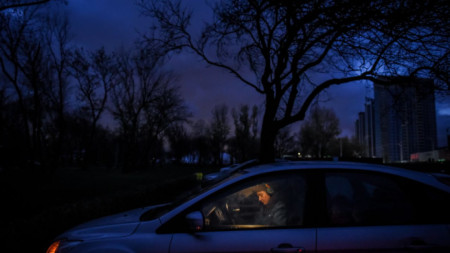Жена е пуснала осветлението на колата си на фона на тъмнината в Киев заради режим на тока в резултат на руските удари